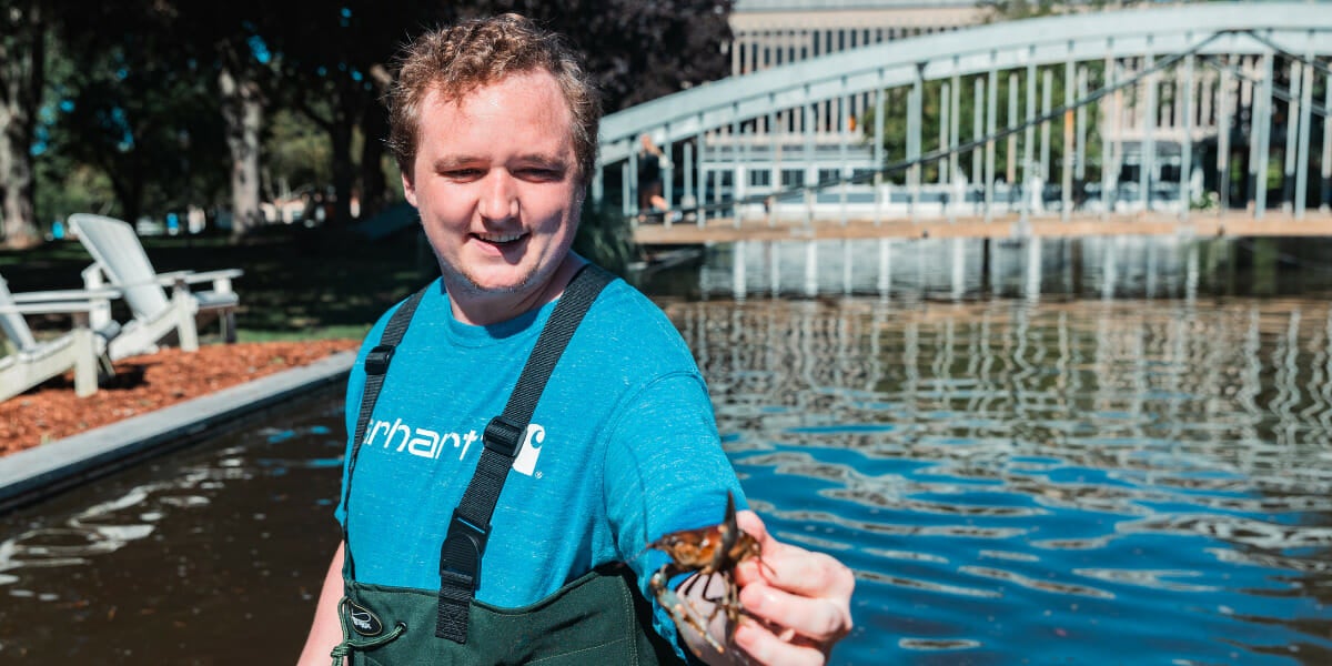 Picture of Griffin McNulty 鈥�24 standing in Mendel Pond holding a crayfish.