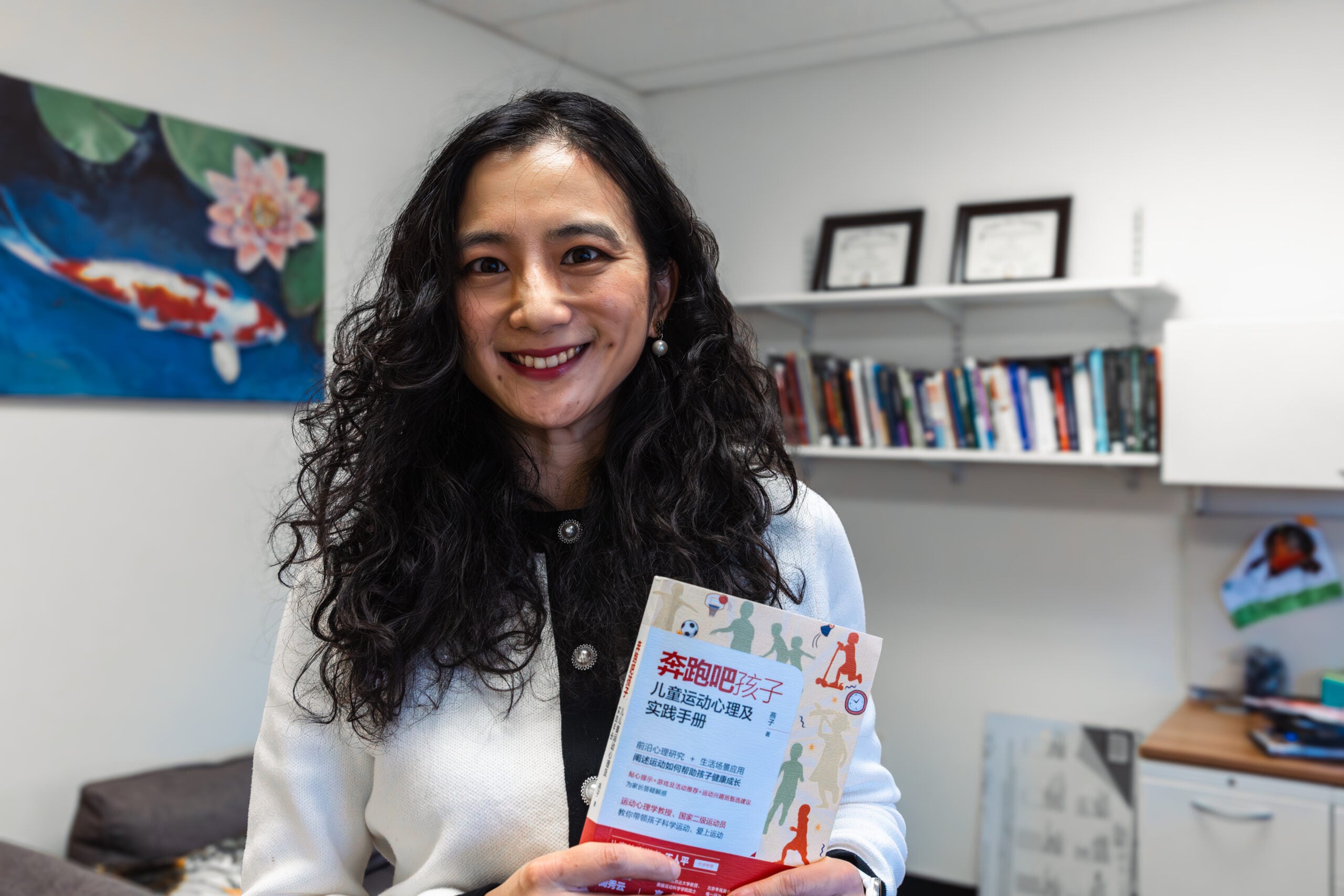 Photo of Zi Yan holding a copy of her book, 鈥淩un Kids: Exercise Physiology and Parents Practice Guide,鈥�