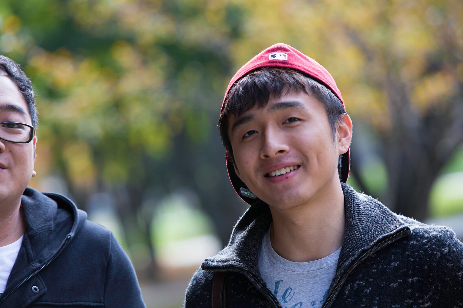 Student with backwards red baseball cap smiling