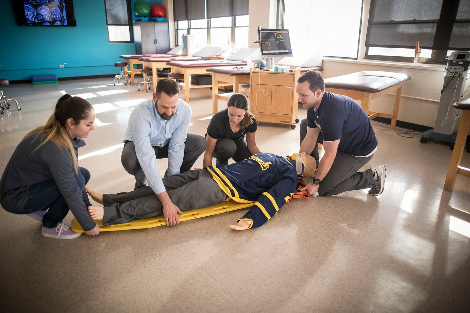 Faculty and students putting Manikin on stretcher